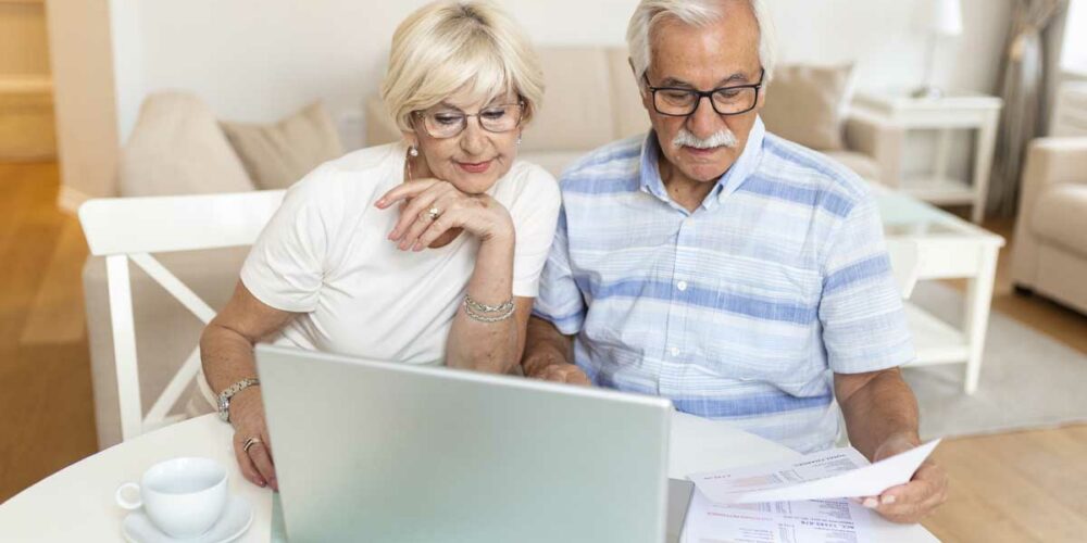 Deux personnes seniors évaluent leur aide OSCAR retraite devant un ordinateur