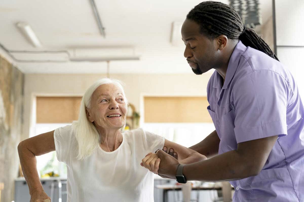 Un aidant qui soutient une personne âgée à tenir sur ses jambes