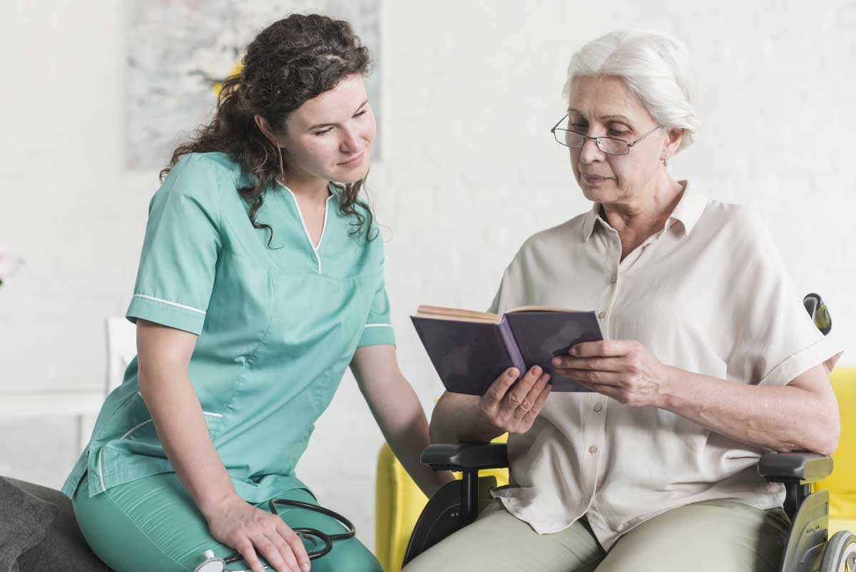 Une infirmière et une femme senior bénéficiant de l'ARDH lisent un livre