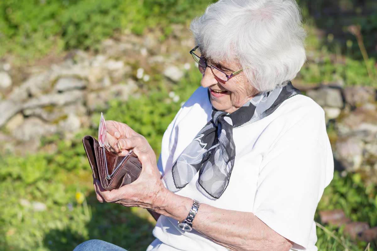 Une femme âgée bénéficie de l'allocation simple d'aide sociale et compte l'argent dans son porte-monnaie