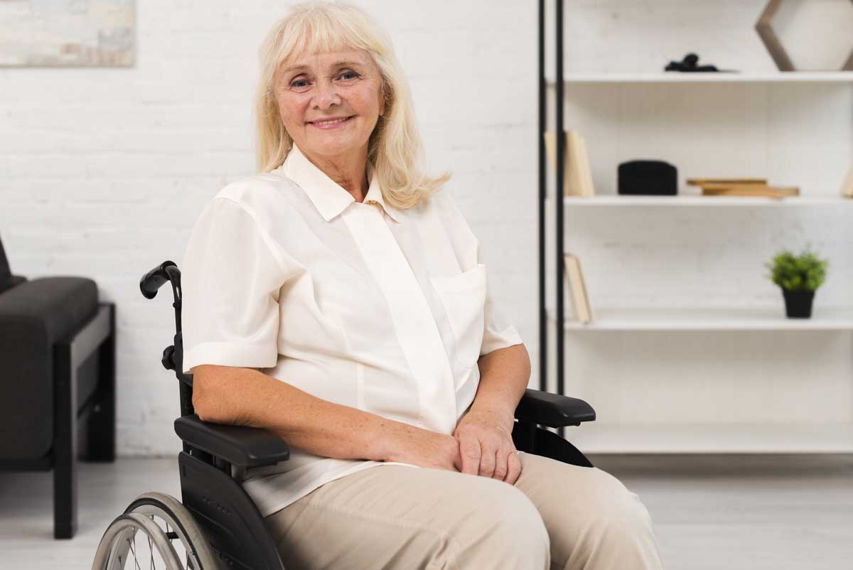 Une femme senior en fauteuil roulant qui peut bénéficier de l'APA ou de la PCH