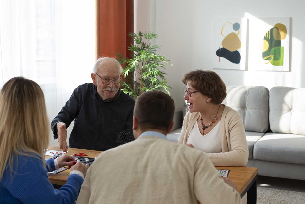 Un accueillant familial, sa famille et le senior accueilli jouent aux jeux de société