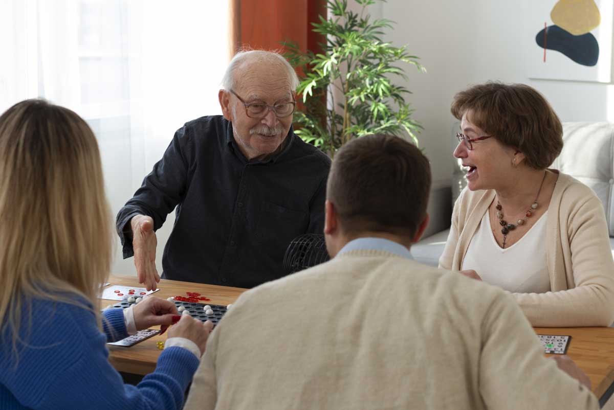 Plusieurs seniors jouent avec de jeunes adultes au sein d'un habitat inclusif