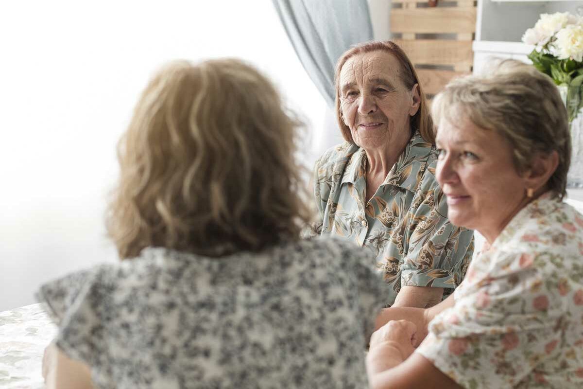 Une femme senior accompagnée de sa fille discute avec la gérante d'un hébergement temporaire