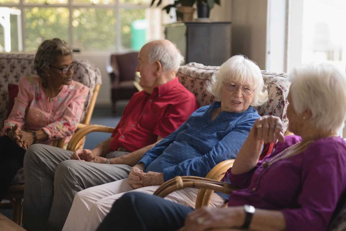 Plusieurs personnes seniors discutent sur un canapé pendant leur hébergement temporaire en EHPAD