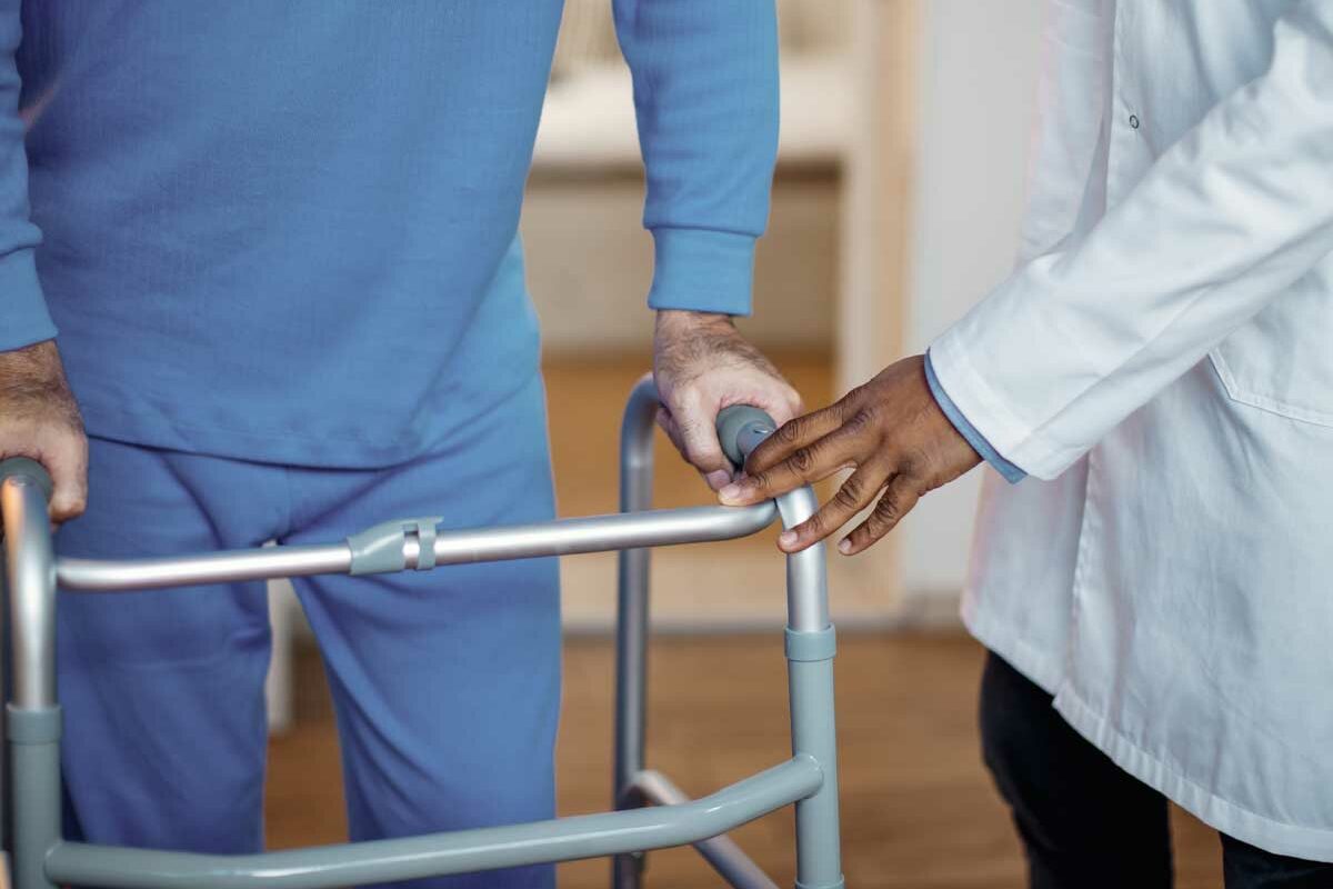 Un homme senior avec un déambulateur avec un soignant qui lui préconise le matériel médical le plus adapté