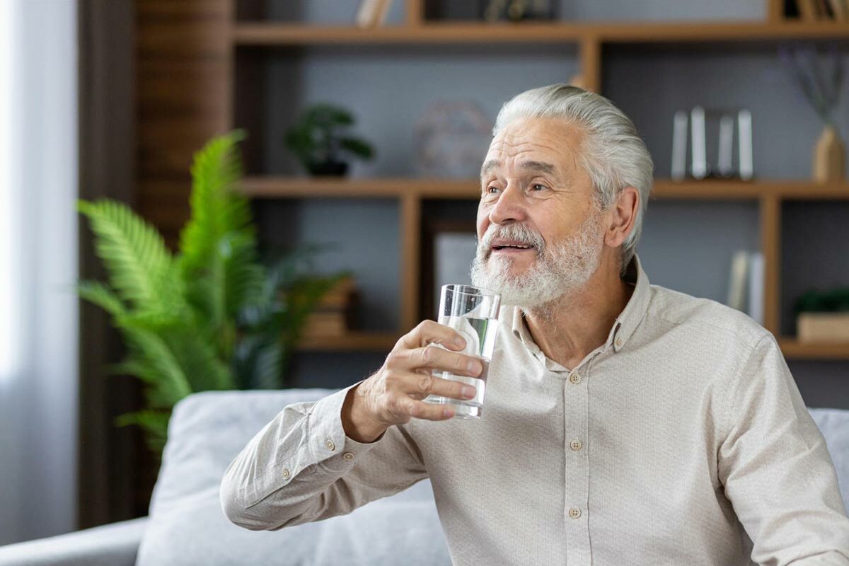 Homme senior qui tient un verre d'eau