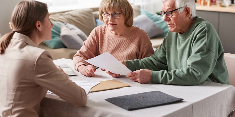 Femme expliquant comment fonctionne la téléassistance à un couple de seniors