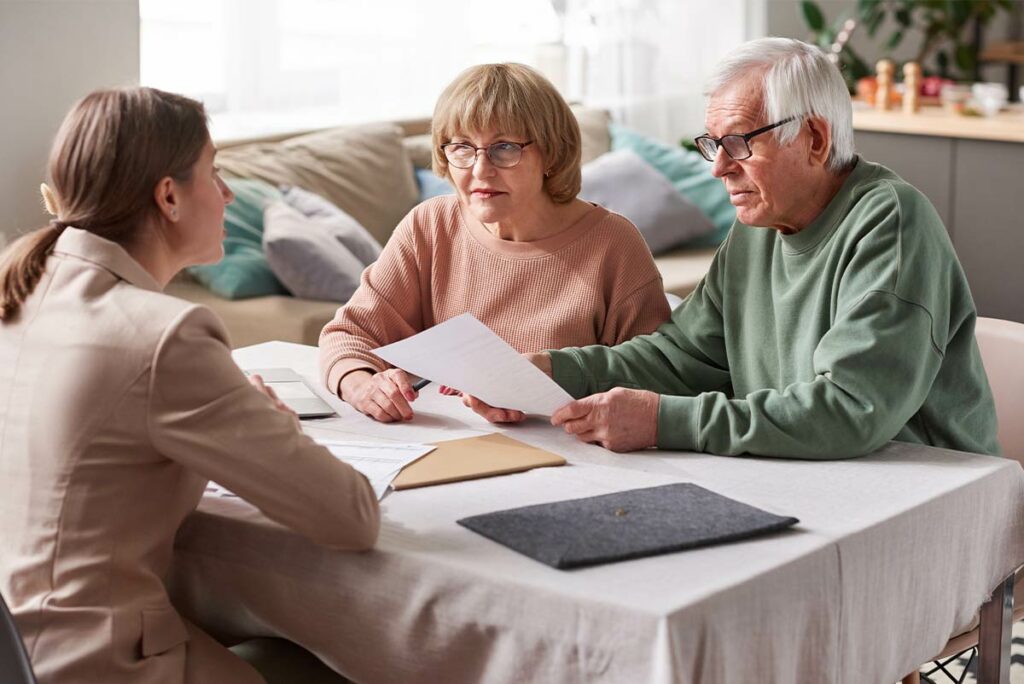 Femme expliquant comment fonctionne la téléassistance à un couple de seniors