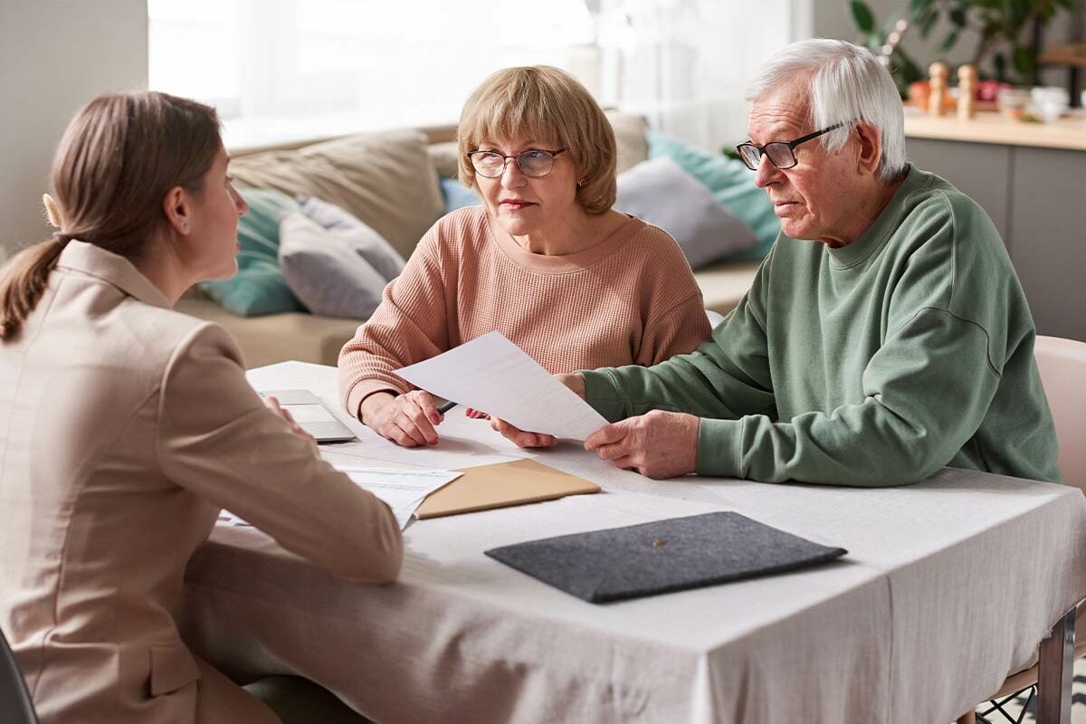 Femme expliquant comment fonctionne la téléassistance à un couple de seniors
